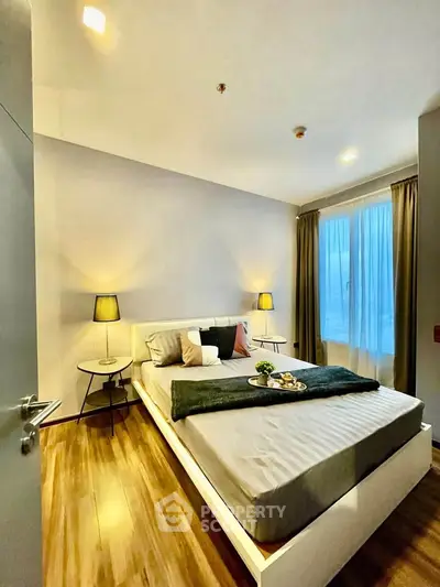 Modern bedroom with stylish decor and natural light, featuring a cozy bed and elegant lighting.