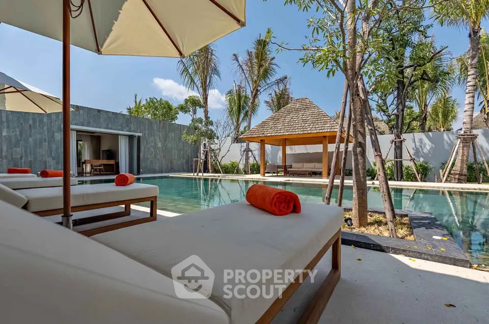 Luxurious outdoor pool area with sun loungers and tropical landscaping in a serene setting.