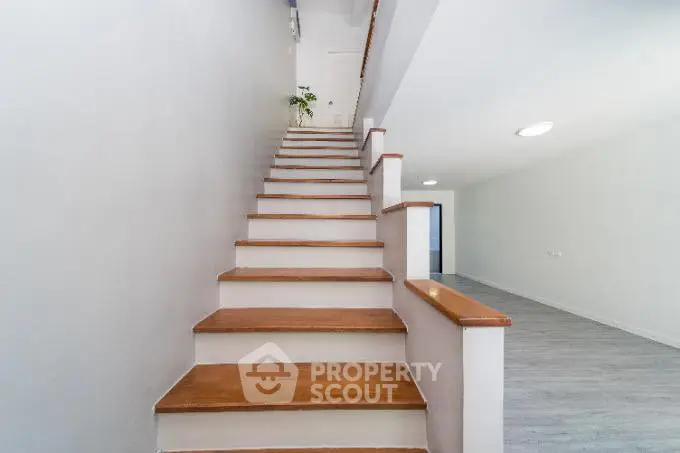 Modern staircase with wooden steps leading to a bright open space