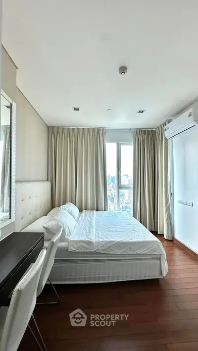 Spacious bedroom with city view, featuring elegant decor and natural light.