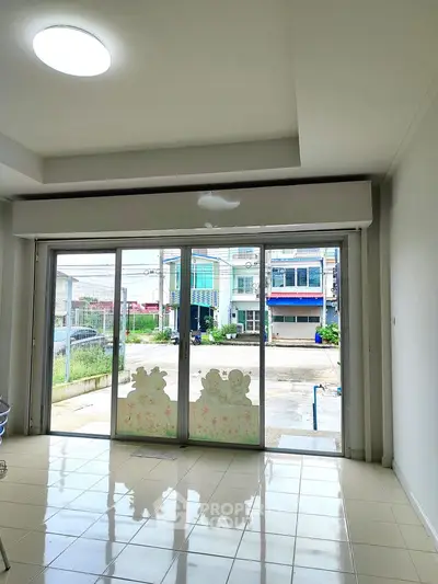 Spacious room with large glass doors leading to a street view, ideal for commercial use.