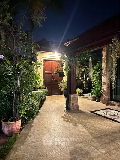 Charming night view of a garden entrance with lush greenery and elegant lighting.