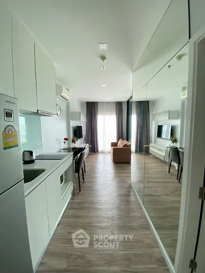 Modern open-layout apartment with sleek kitchen and cozy living area, featuring large windows and stylish decor.