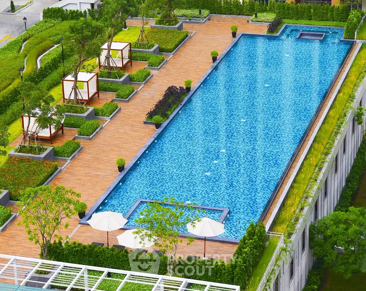 Luxurious rooftop pool with lush greenery and cabanas in a modern residential complex.