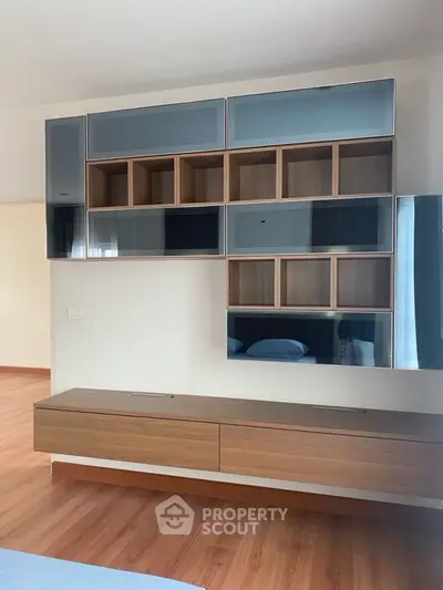 Modern living room with sleek wooden cabinetry and mirrored accents