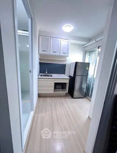 Modern compact kitchen with sleek appliances and stylish cabinetry in a cozy apartment setting.