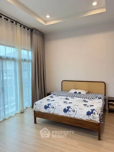 Spacious bedroom with large windows and stylish decor in modern apartment.