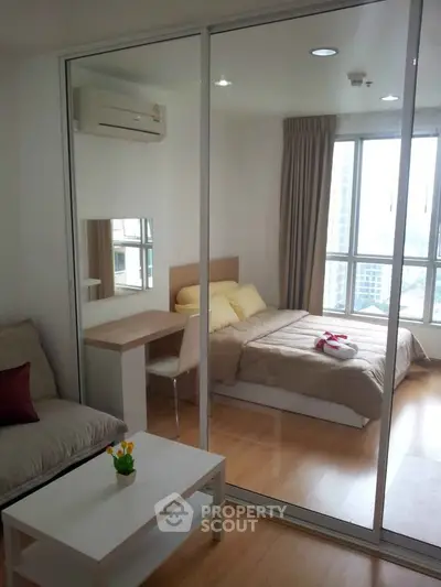 Modern studio apartment with glass partition, cozy bed, and city view.