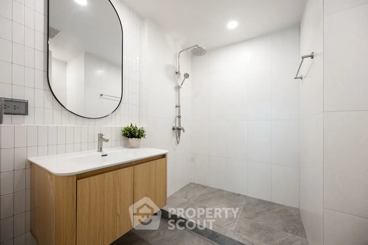 Modern bathroom with sleek design, featuring a spacious shower and elegant vanity.