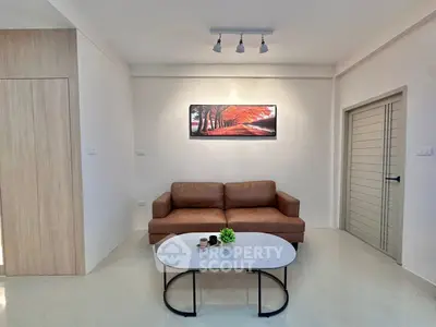 Modern living room with brown sofa, stylish coffee table, and wall art in a minimalist design.