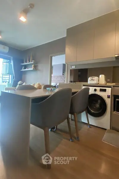Modern kitchen with integrated washing machine and dining area in stylish apartment.