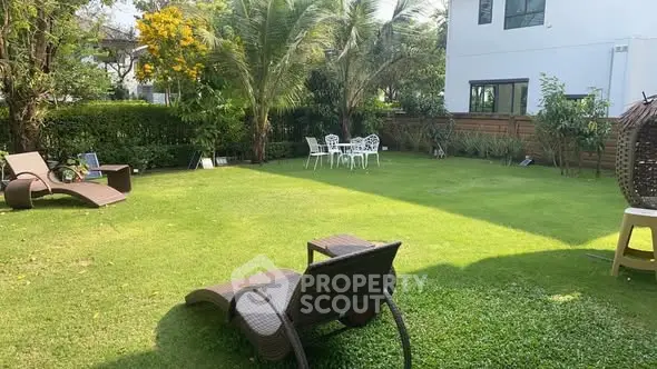 Spacious garden with lush greenery and outdoor seating in a modern home setting.