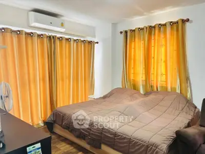 Cozy bedroom with warm lighting and elegant curtains, featuring a comfortable double bed and air conditioning.