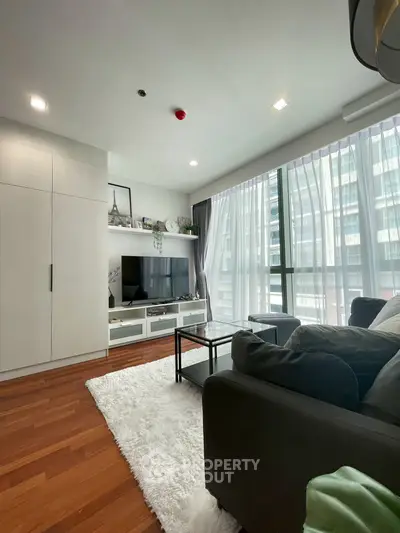 Modern living room with large windows and stylish furniture in a high-rise apartment.