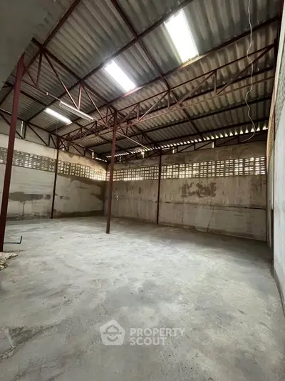 Spacious industrial warehouse with high ceilings and ample natural light, perfect for storage or manufacturing needs.