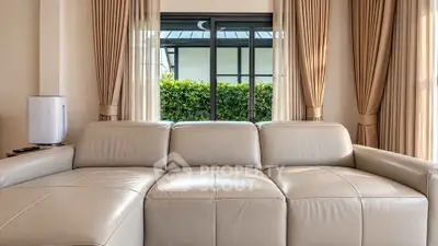 Luxurious living room with elegant leather sofa and large windows overlooking greenery.