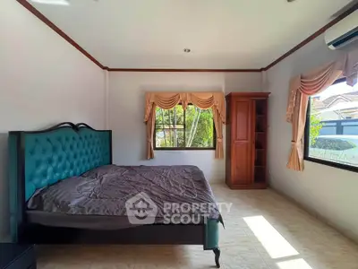Spacious bedroom with elegant decor and large windows offering natural light and garden views.