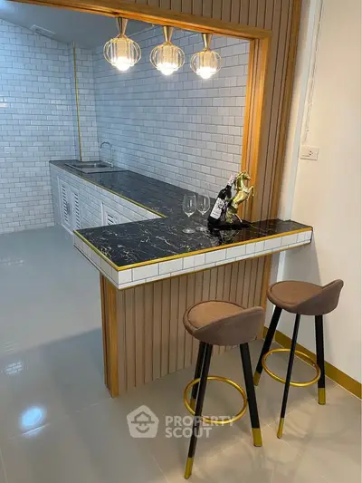 Stylish modern kitchen with elegant bar counter and chic lighting, perfect for entertaining guests.