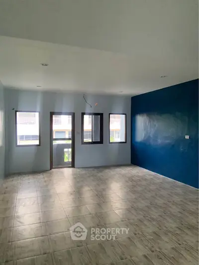 Spacious empty room with large windows and blue accent wall, perfect for customization.