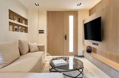 Modern living room with sleek design, featuring a cozy sofa, glass coffee table, and wall-mounted TV.