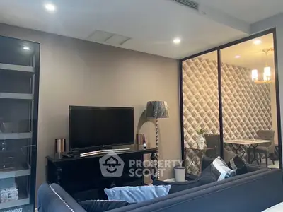 Stylish living room with modern decor and adjacent dining area, featuring elegant lighting and patterned wallpaper.