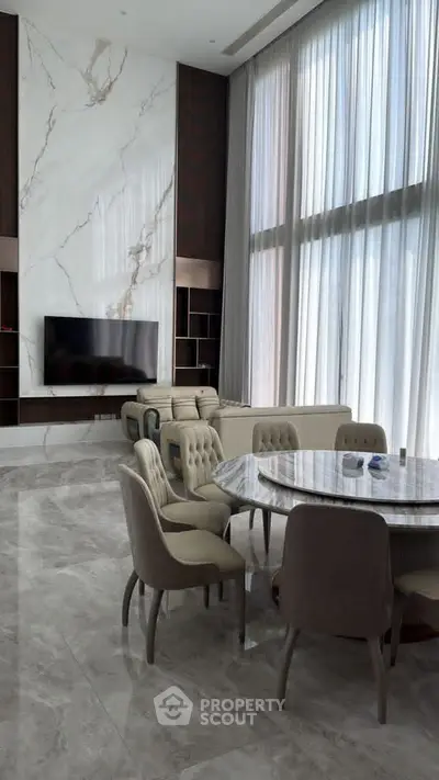 Luxurious living room with high ceilings, marble accents, and elegant furniture.