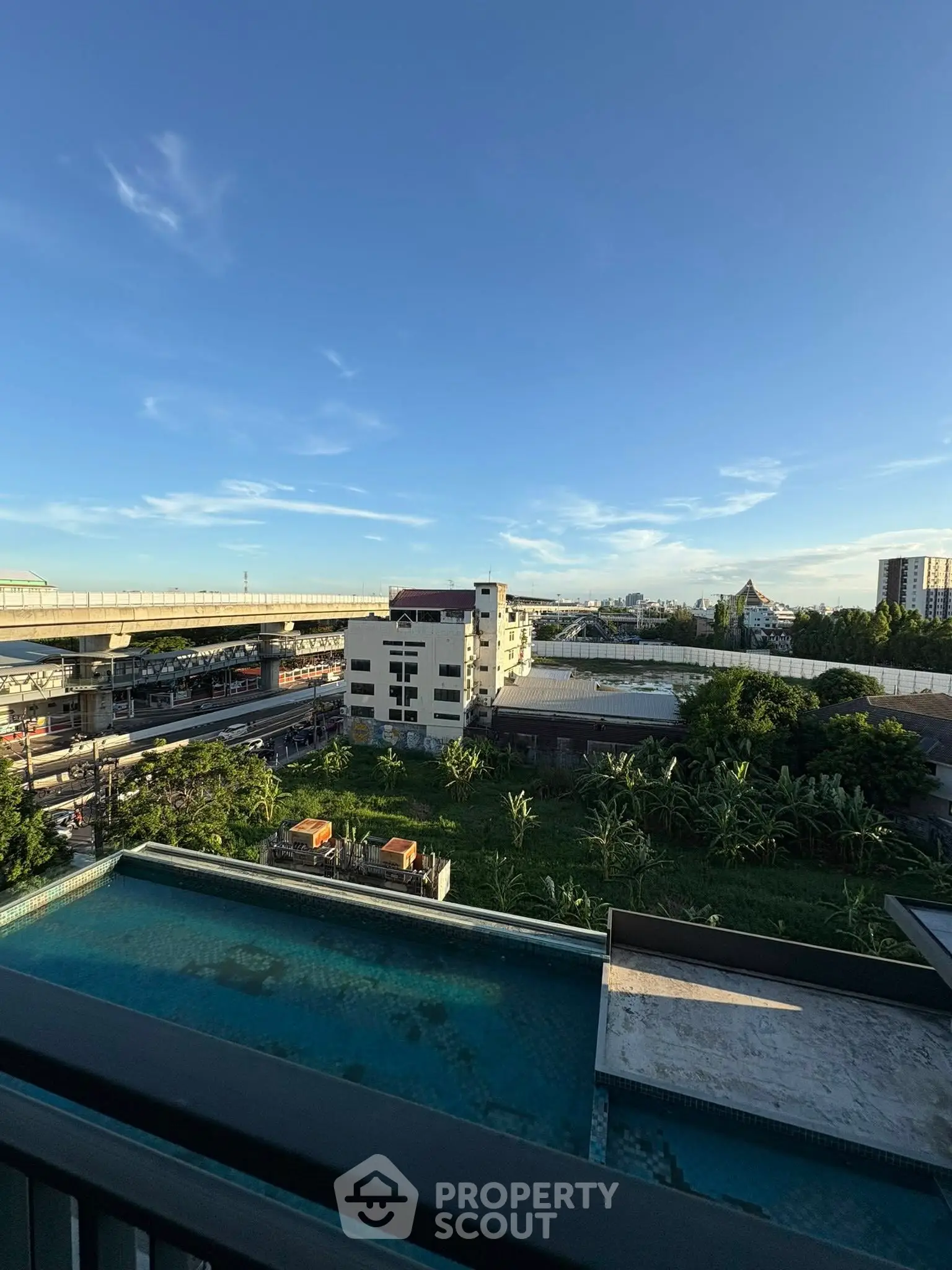 Stunning cityscape view from a high-rise balcony overlooking urban skyline and lush greenery.