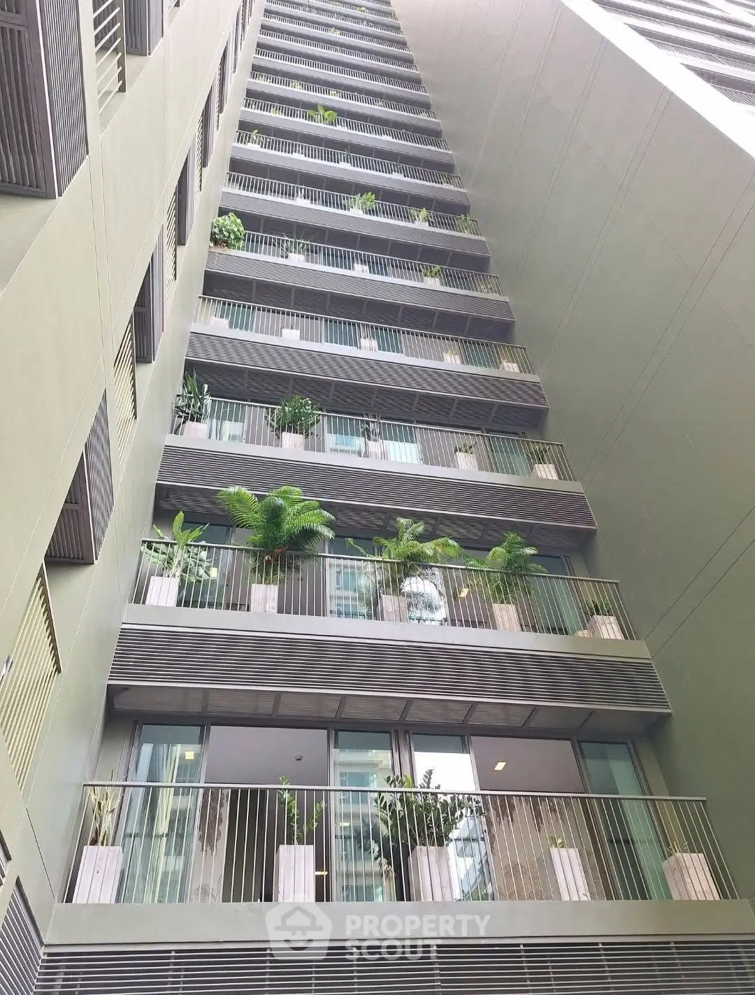 Modern high-rise building with lush balcony greenery and sleek architectural design.