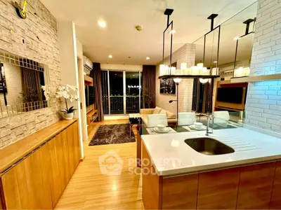 Modern open-layout living room with kitchen, featuring elegant lighting and balcony view.