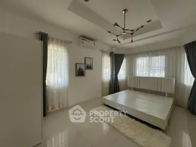 Spacious bedroom with modern lighting and large windows for natural light.