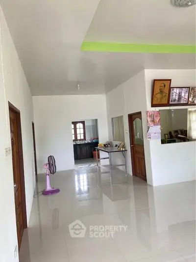 Spacious open layout living area with glossy tiled floors and natural light.