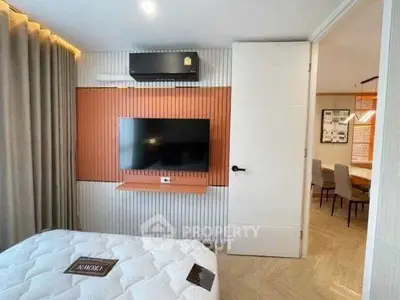 Modern bedroom with wall-mounted TV and stylish decor, adjacent to a dining area.