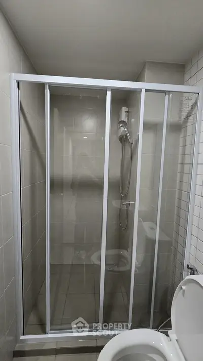 Modern bathroom with glass shower enclosure and tiled walls.
