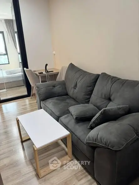 Cozy living room with plush gray sofa and modern coffee table in stylish apartment.