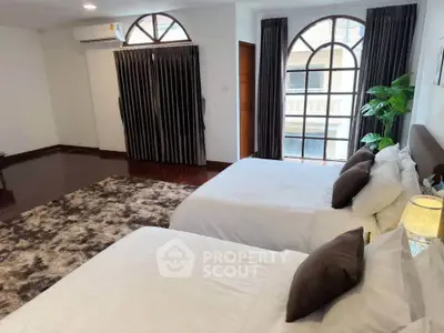 Spacious bedroom with elegant decor and large windows for natural light.