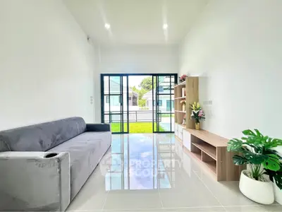 Modern living room with sleek furniture and large glass doors opening to a garden view.