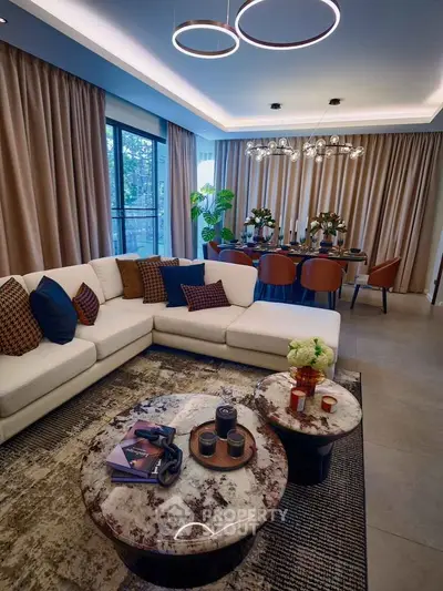 Luxurious living room with modern decor and elegant dining area, featuring stylish lighting and plush seating.