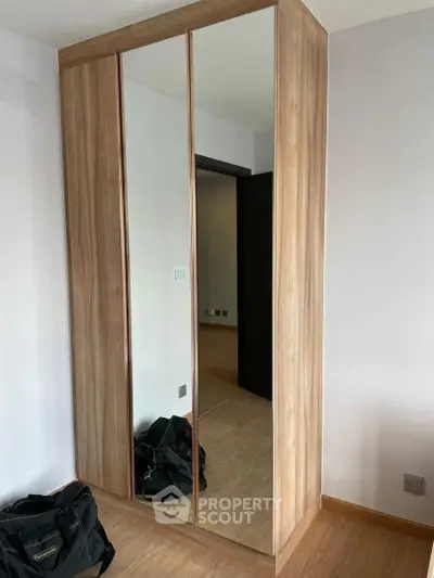 Modern bedroom with sleek mirrored wardrobe and wooden flooring
