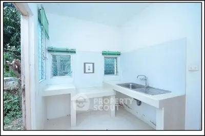 Bright kitchen with dual windows and stainless steel sink, perfect for culinary enthusiasts.