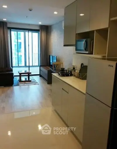Modern open-layout kitchen and living room with balcony view in a stylish apartment.