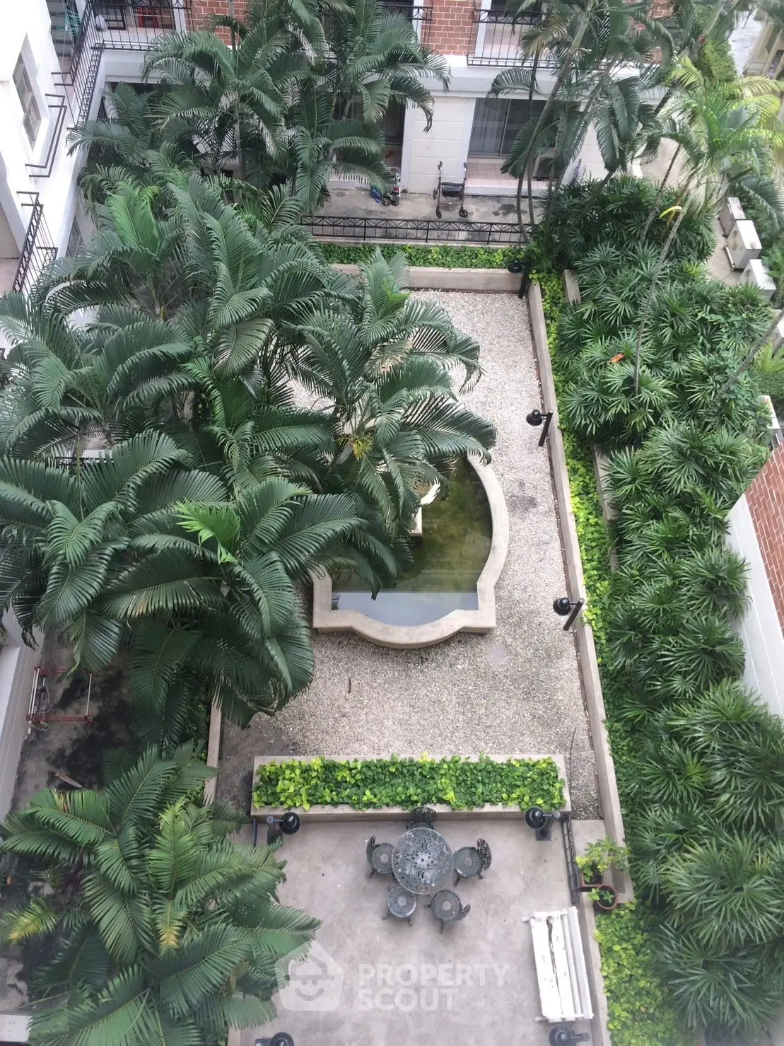 Lush garden courtyard with palm trees and elegant stone fountain
