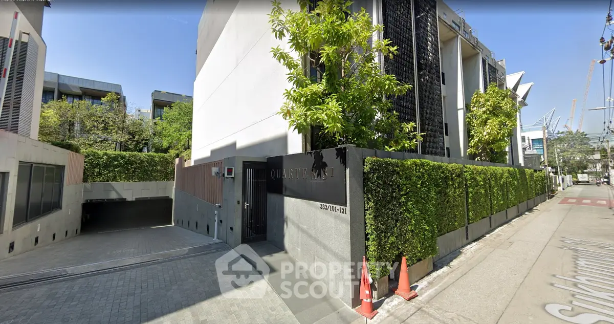 Modern building exterior with lush greenery and sleek design in urban setting.