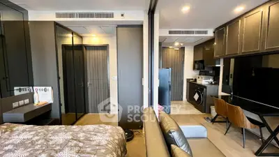 Modern studio apartment with sleek kitchen and cozy living area, featuring stylish decor and ample natural light.