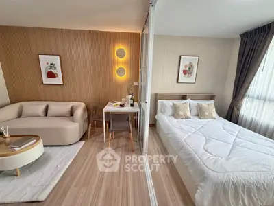 Modern studio apartment with stylish living area and cozy bedroom separated by glass partition.