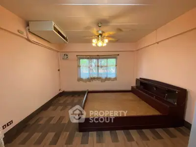 Spacious bedroom with wooden flooring and ceiling fan, featuring a built-in wooden bed frame.