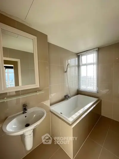 Modern bathroom with sleek bathtub and large window offering natural light.
