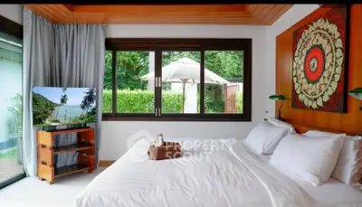 Luxurious bedroom with large window view and elegant decor in tropical setting.