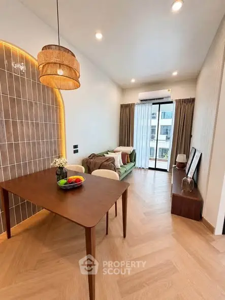 Modern living room with stylish decor, wooden dining table, and large window offering natural light.