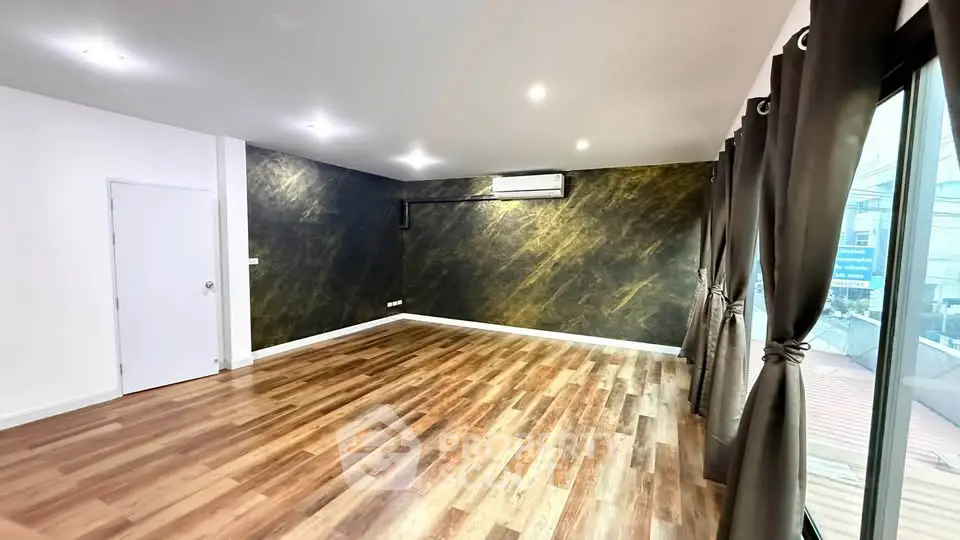 Spacious modern living room with elegant wood flooring and large windows for natural light.