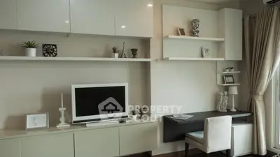 Modern living room with sleek shelves and stylish decor, featuring a TV and cozy study nook.